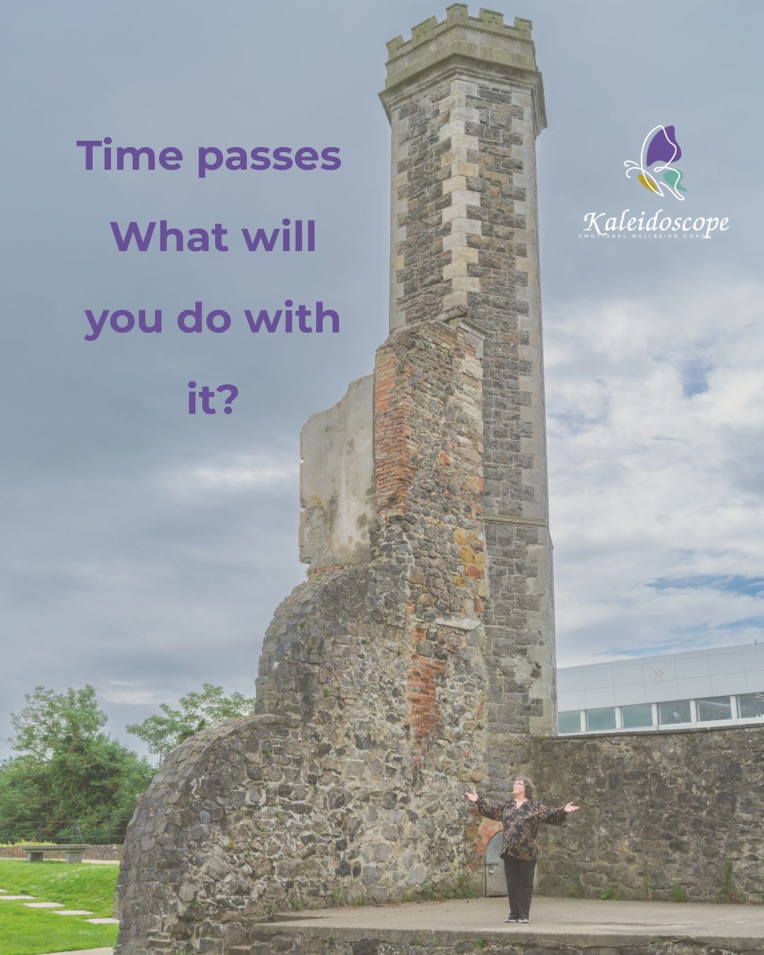 A woman stands with arms open in front of a tall historic stone tower, reflecting on time, life, and emotional wellbeing.